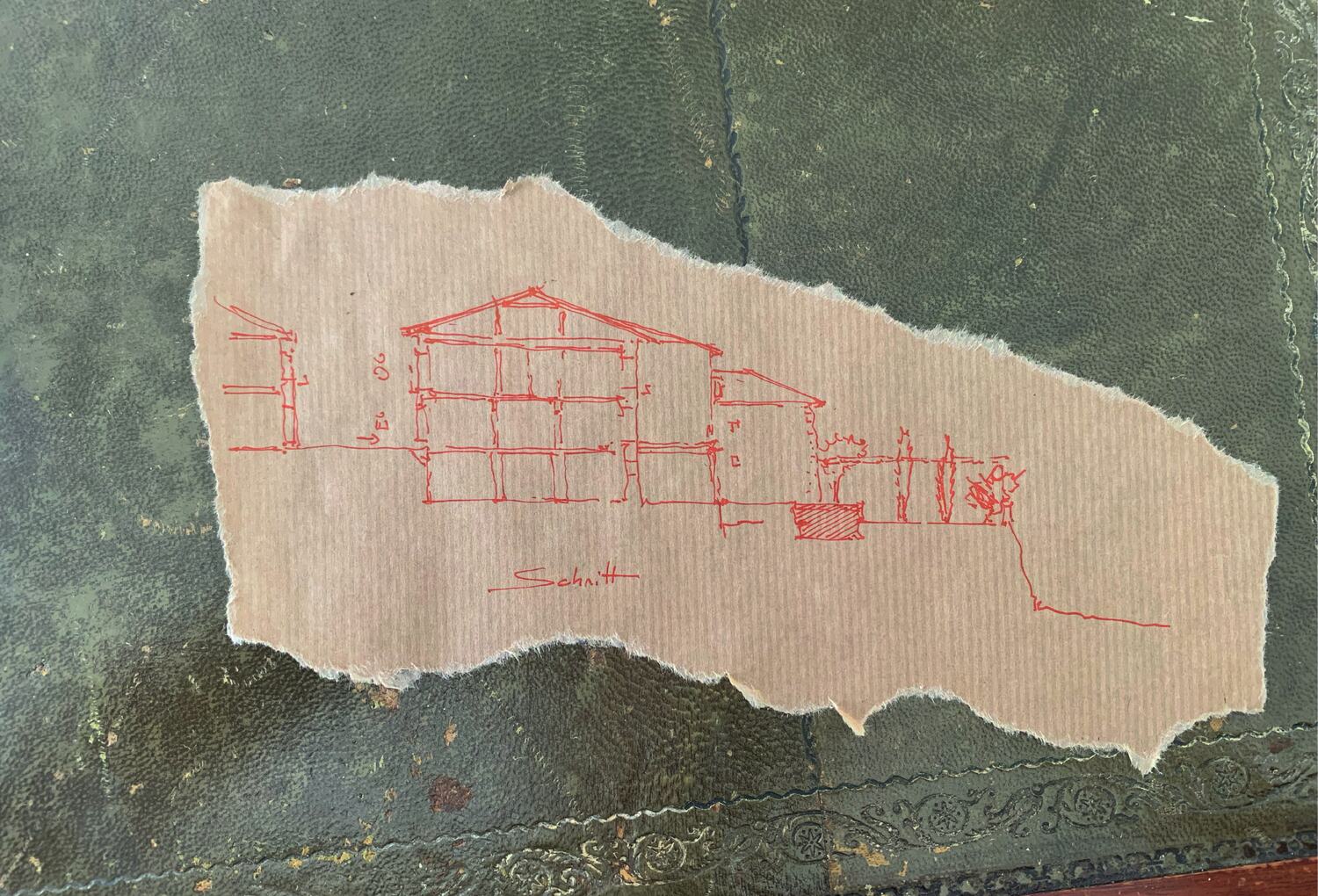 An early drawing of the house in red ink on torn paper